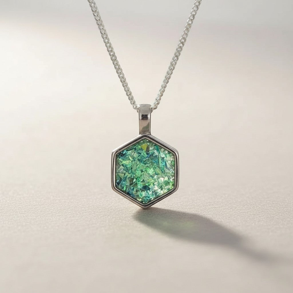 Ashes In Jewellery silver hexagon memorial pendant with green iridescent ashes. A meaningful tribute.